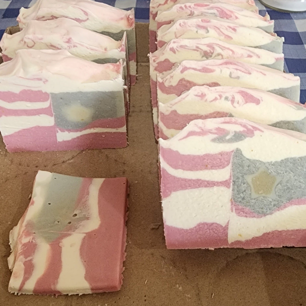 Old Glory goat milk soap: rows of freshly cut bars with red, white, and blue marbling on a cardboard surface.