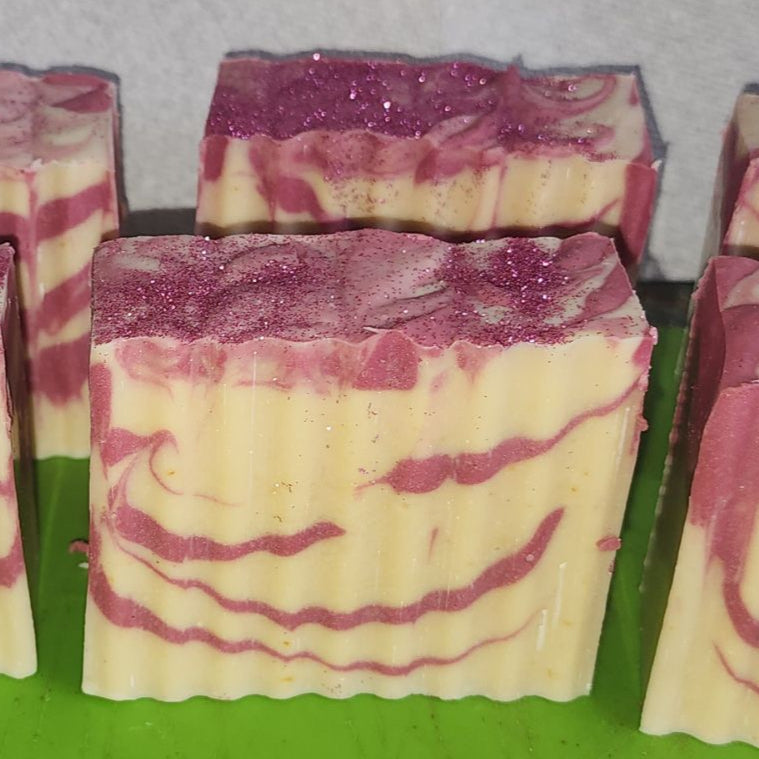 Cream-colored bar soap with dark pink swirled patterns and glitter on top.