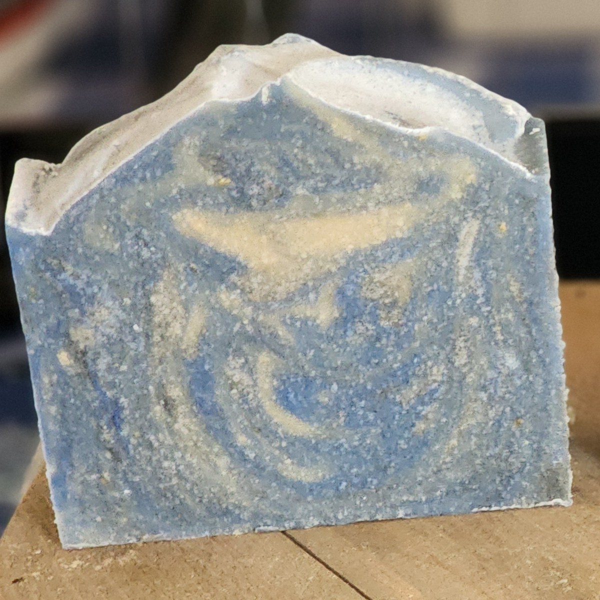 Kentucky Bourbon goat milk soap: one bar with blue, white, and gray swirls and a frosted top, sitting on a wooden surface.